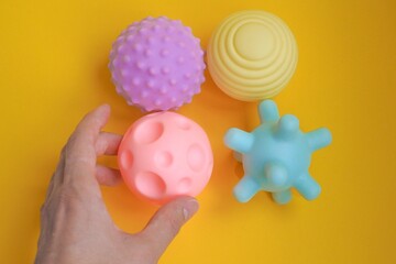 Hand holding a colorful sensory soft ball for babies and kids. Concept of massage textured balls...