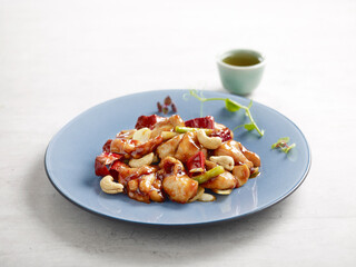 Stir-fried Kung Pao Chicken served in a dish side view on grey background