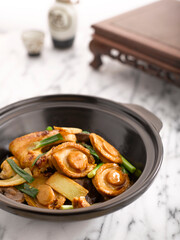 Braised Chicken and Abalone with Abalone Sauce served in Casserole served in a pot side view on grey background