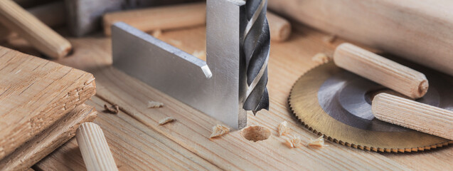 Fototapeta na wymiar drill bit with steel triangle ruler make sink in hole for screw in wooden oak plank