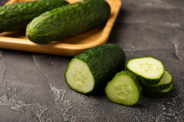 Fresh organic cucumbers whole and slices on wooden texture background.Ingredient for salad.Fresh vegetables.Vegan food.Healthy food.Fresh organic vegetable.Copy space.