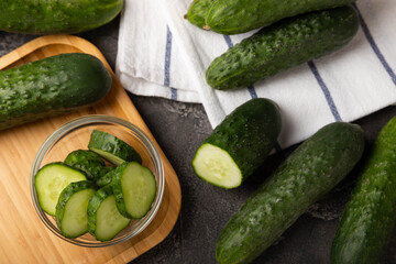 Fresh organic cucumbers whole and slices on wooden texture background.Ingredient for salad.Fresh vegetables.Vegan food.Healthy food.Fresh organic vegetable.Copy space.