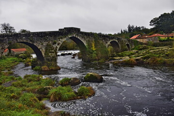 Fototapeta na wymiar Old stone bridge with arches across the river. The Way of St. James, Northern Route, Spain.