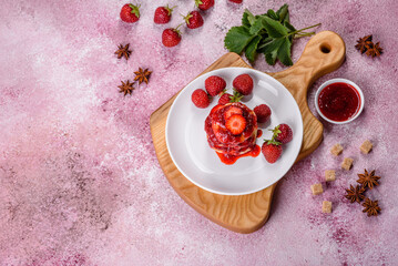 Cottage cheese pancakes with sliced strawberries and strawberry jam on a plate on a concrete background
