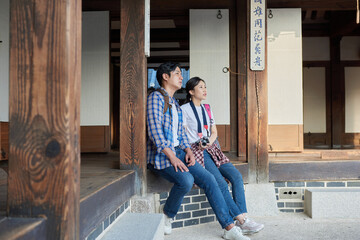 Obraz na płótnie Canvas 한국의 옛날 전통 가옥 마루에 앉아 즐겁게 이야기를 나누고 있는 젊은 아시아 한국 남녀 모델