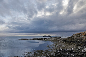 Flatey, Iceland, May 5, 2022: approaching ferryboat Baldur seen from a rocky beach next to the harbor