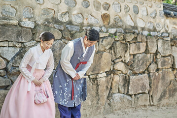 Obraz na płótnie Canvas 한복을 입고 한국의 전통 가옥 담장을 배경으로 커플 여행자 아름답고 멋진 젊은 아시아 한국 남녀 모델