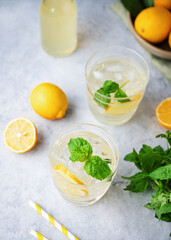 Lemonade soda drink with fresh lemons. Refreshing cocktail with lemon, mint and ice on blue background. Summer cold drinks concept. Top view