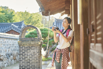 Fototapeta na wymiar 한국의 옛날 전통 가옥 건물을 배경으로 여행 또는 사진촬영 하고 있는 대학생 젊은 아시아 한국 여자 모델