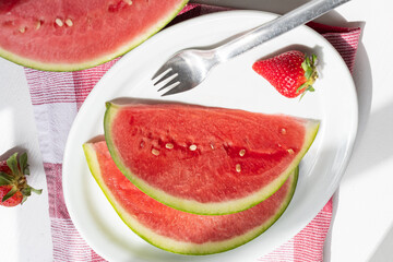 Summer berry, slices of juicy watermelon on a plate on a white table.