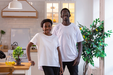 African american couple in love in white t-shirts stand in the kitchen. Mock-up.