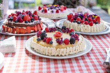 Homemade cakes from summer berries and edible flowers on the festive table.
