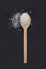 Fototapeta na wymiar wooden spoon with sea salt on black background