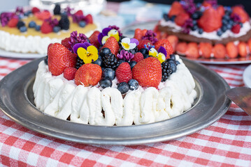 Homemade cake with whipped cream, berries and edible flowers, dessert for holiday.