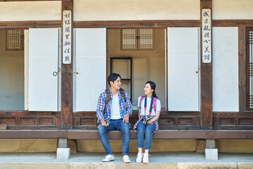 Obraz na płótnie Canvas 한국의 옛날 전통 가옥 마루에 걸터 앉아서 서로 바라보며 즐겁게 대화 또는 설명하고있는 아시아 한국 남자 여자 모델