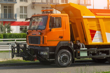 Orange special cleaning services harvest truck with a converted interchangeable tool in front.