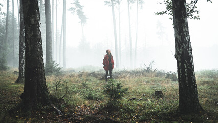 A woman stands in a wet and foggy forest. Czech republic, Bohemian Switzerland