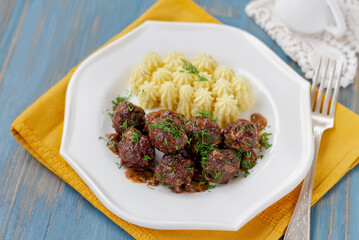 Mini meatballs with mashed potatoes piped into pretty swirls on white plate. Selective focus, horizontal.