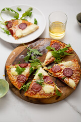  pizza sliced on wooden plate and beer in glass white surface