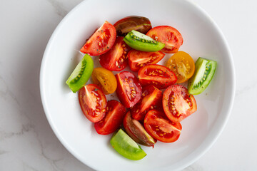 Overhead view of sliced tomato in white bowl