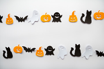 White background with Halloween decor ghost bat pumpkin copy space from above