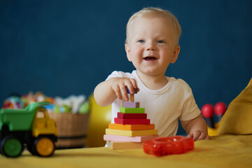 Cute baby boy playing with toys while sitting on the floor at home. Early development of children. happy childhood. Advertisement for children's products