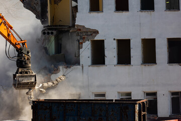 Close up of a bucket of an excavator demolishing an old building. Dangerous demolition works in the...