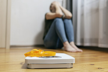 White scale and depression, upset and sad woman with measuring tape on wooden floor