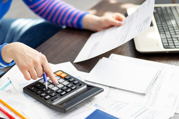 Woman using calculator for calculate domestic bills at home, doing paperwork for paying taxes