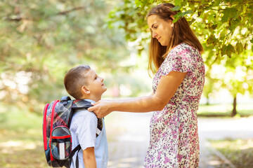 Back to school. Mother saying goodbye to her son as he leave for School. Schoolboy is ready go to...