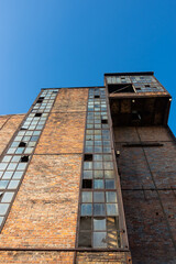 Ruins of an abandoned industrial plant. Brick walls against the background of the blue sky. Photo taken on a sunny day.