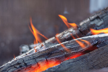 Defocused Firewood is burning in the fireplace in the flames of a warm red fire on a dark background. Briquettes glow and burn, close up