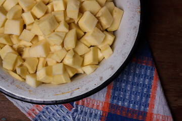 Bowl of cut sweet potato or yam on wooden table with kitchen towel. Top view. Nutricious tasty vegetarian food, local farmer harvest