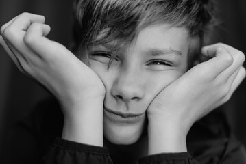 Black and white portrait of teenage boy on dark background. Low key close up shot of a young teen boy. Black and white photography. Selective focus