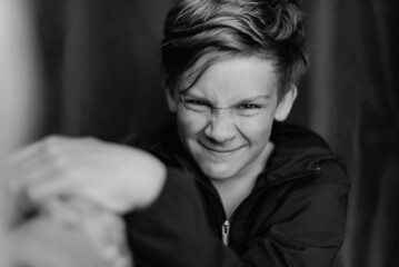 Black and white portrait of teenage boy on dark background. Low key close up shot of a young teen boy. Black and white photography. Selective focus