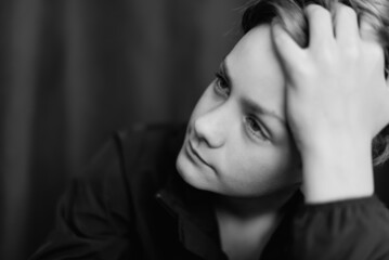 Black and white portrait of teenage boy on dark background. Low key close up shot of a young teen boy. Black and white photography. Selective focus