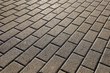 Stone pavement texture, cobbled street in sunlight. Road from tiles