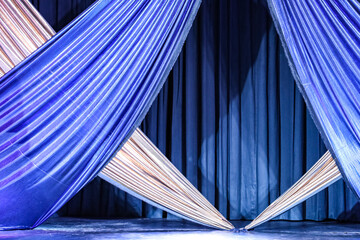 Bright braided front curtains in the blue and silver colors of a stage, in the background another blue curtain.
