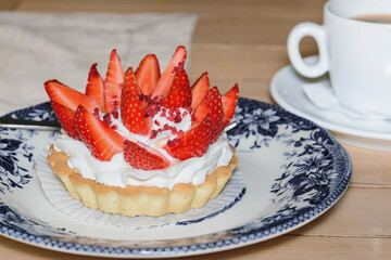 cake basket with buttercream and fresh strawberries on top. Cupcake dessert and coffee in a cafe.