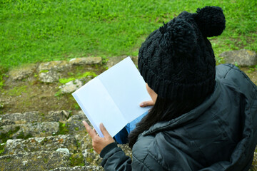 Mujer latina viendo un libro en blanco con espacio para texto. Vista horizontal.