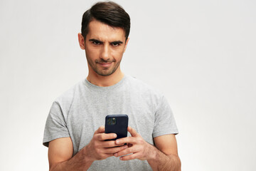 handsome man in a gray t-shirt with a phone communication technology cropped view