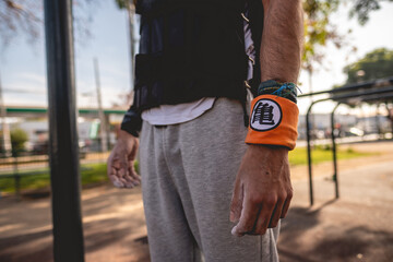 Fit and handsome athletic guy with a weight vest and wristband in a calisthenics and street workout...