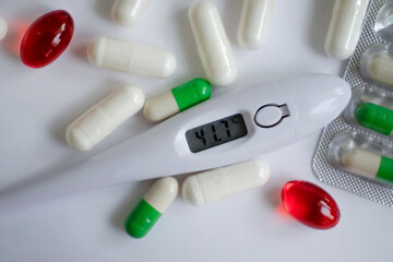 Thermometer, pills on a light background