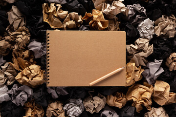 Notepad or notebook on crumpled paper balls as background texture. Inspiration idea concept