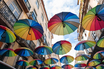 Fototapeta na wymiar Beautiful stylish rainbow umbrellas fly over the street in Lisbon, Portugal. Creative idea