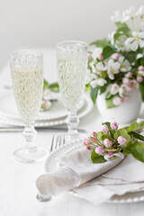 Beautiful table decor for a wedding dinner with a spring blooming apple tree flowers. Celebration of a special event. Fancy white plates, wineglasses