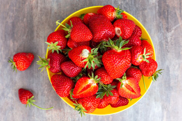 Cup with red ripe strawberries on the table, top view, flat lay. Delicious summer harvest of fruits and berries