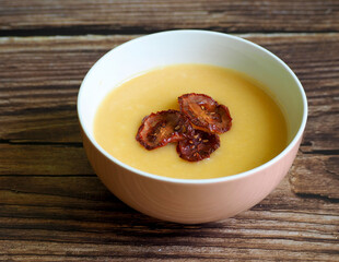 on a wooden table there is a round plate of vegetable soup with mashed potatoes, carrots, onions, parsley root, decorated with three boats of dried tomatoes. restaurant. cooking. gluten-free