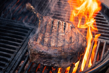 Barbecue dry aged wagyu tomahawk steak offered as close-up on a charcoal grill with fire and smoke