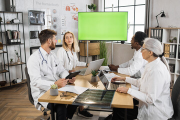 Qualified male and female therapists in white lab coats having morning briefing at hospital office....